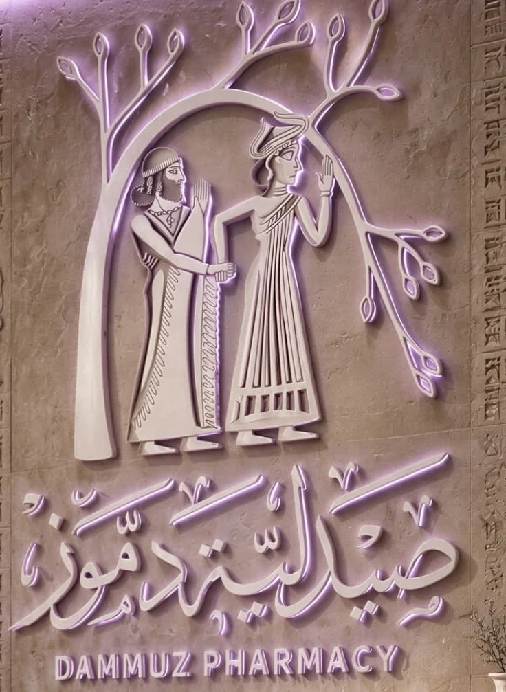 شعار صيدلية دموز: رجل وامرأة تحت شجرة الحياة بنقش سومري مضاء باللون البنفسجي